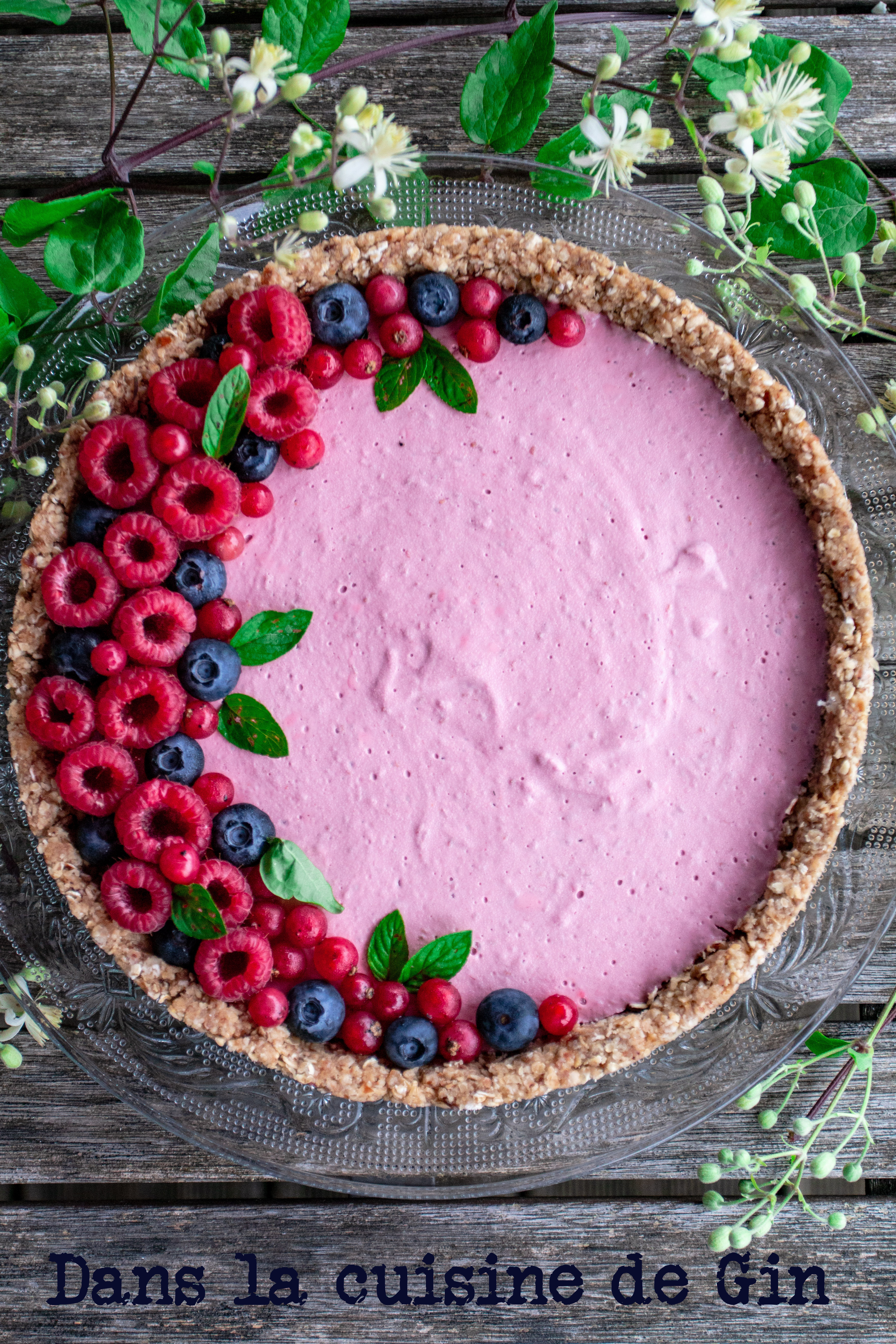 Tarte à la framboise décorée de fruits rouges sur fond de fleurs sauvages